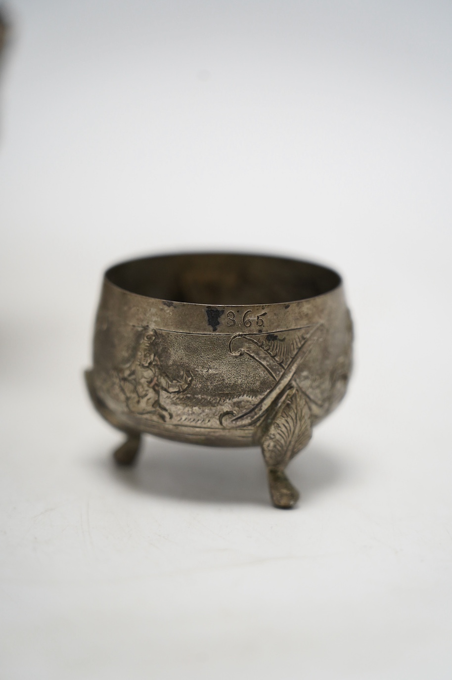 An Indian repousse white metal pedestal bowl, diameter 15.5cm (a.f.), a similar mug, small vase, condiment and small beaker. Condition - poor to fair